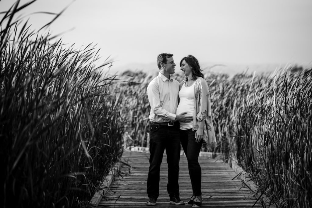 expectant mother standing with father on a wooden walkway