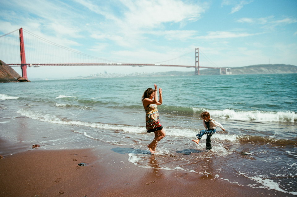 mother and daughter playing in the water with golden gate bridge in the background
