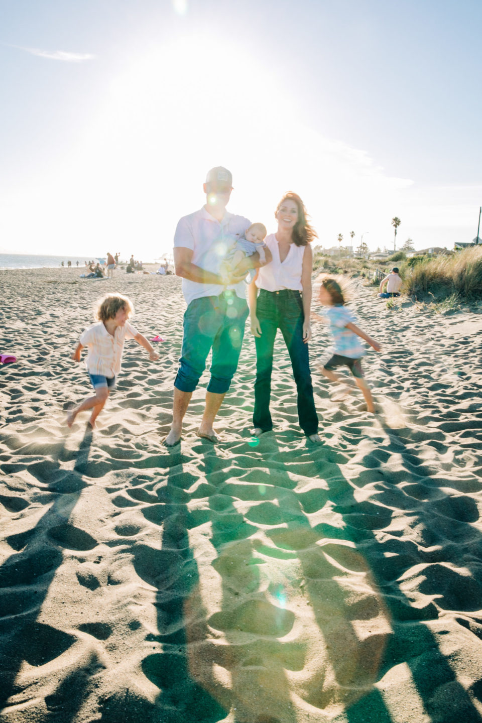 family of five on the beach with sun flare