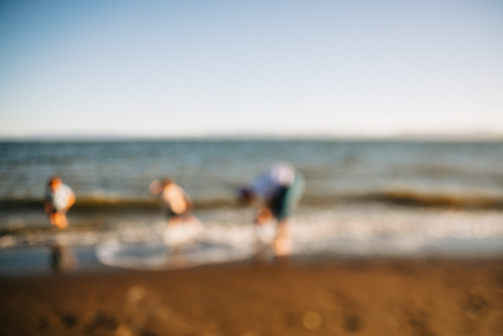 out of focus photo of three people on beach