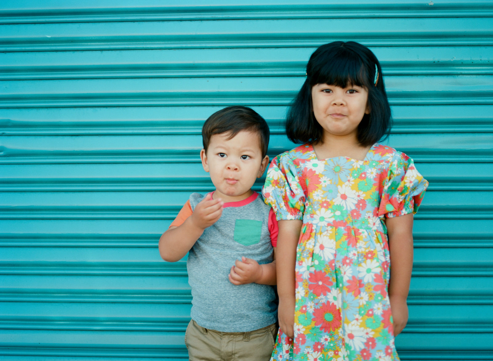 young boy and girl standing in front of blue wall