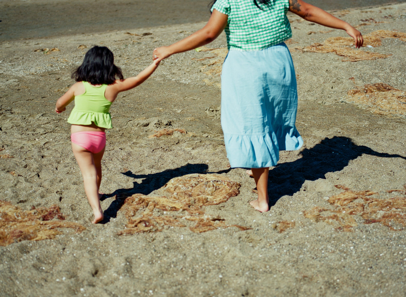 mother and daughter running towards ocean