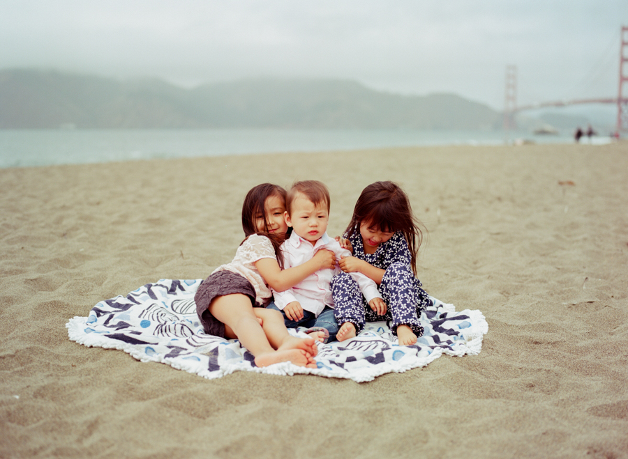 three kids on a circular blanket on baker beach in san francisco