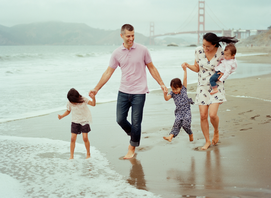 family of 5 on the beach in front of golden gate bridge