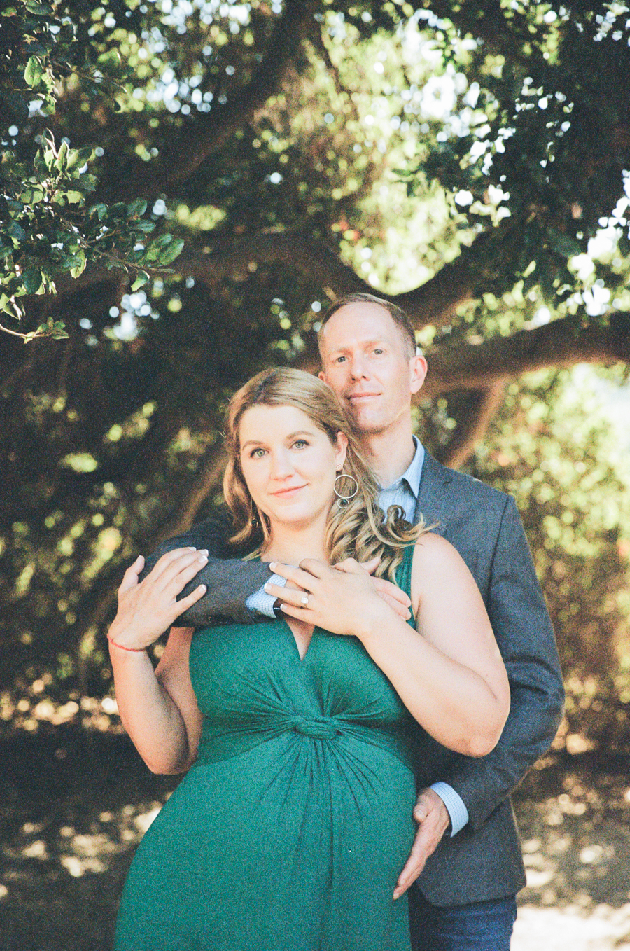 pregnant wife with husband standing and holding her from behind
