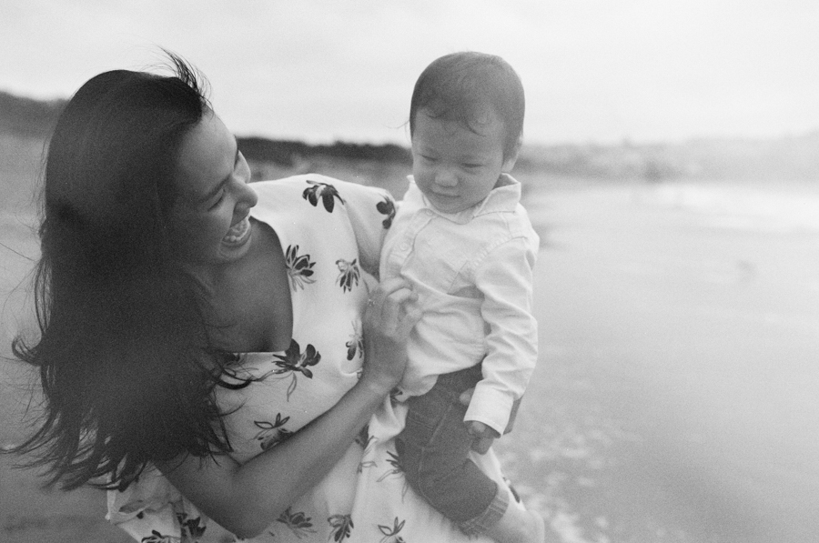 black and white photos of mom holding son on baker beach in san francisco