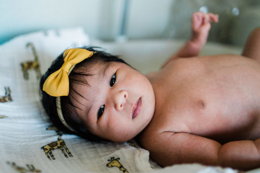 newborn baby girl with yellow bow on her head