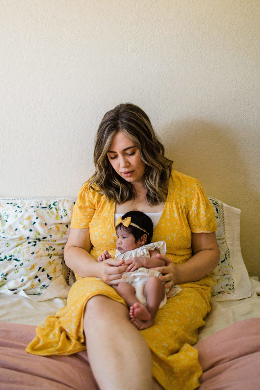 mother in yellow dress holding newborn daughter