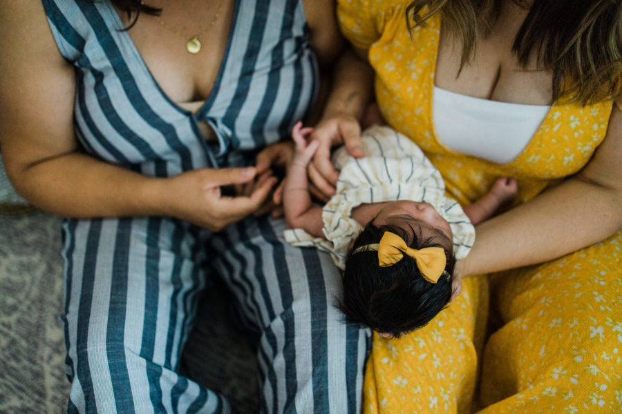 overhead view of same sex couple holding newborn baby girl