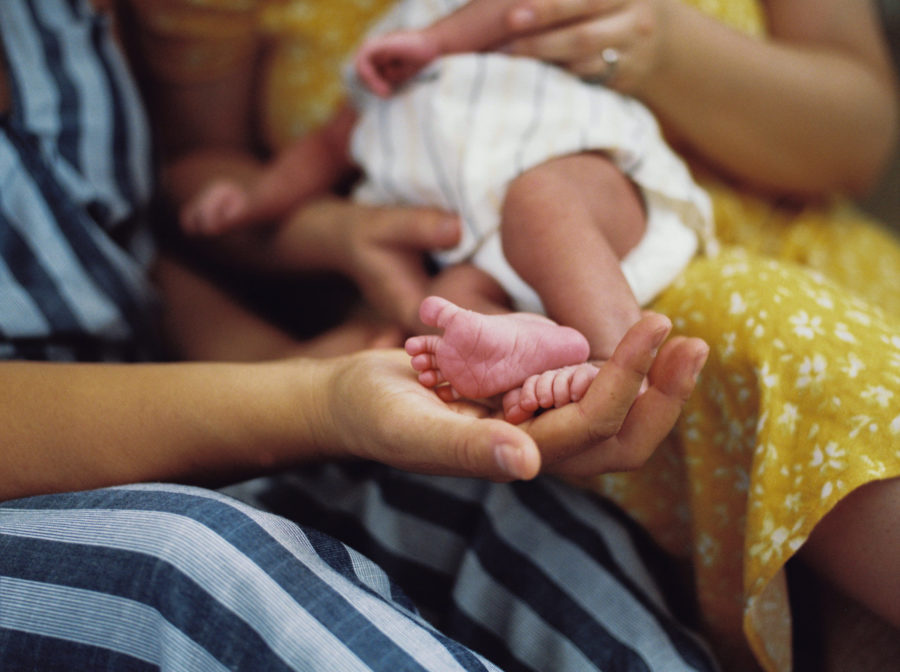 newborn baby toes being held by mom's hands