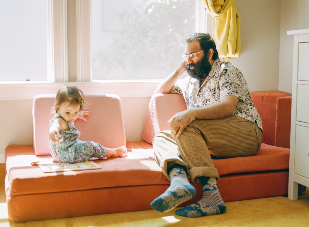 baby girl and dad sitting on a nugget couch by the window