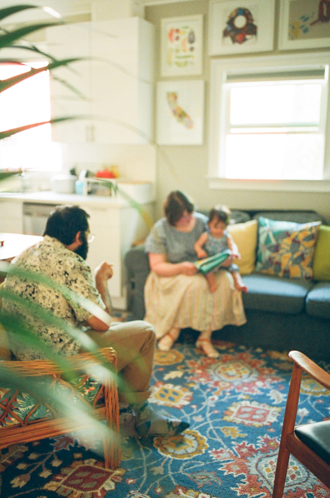 out of focus photo of mom and baby sitting on couch with dad looking on