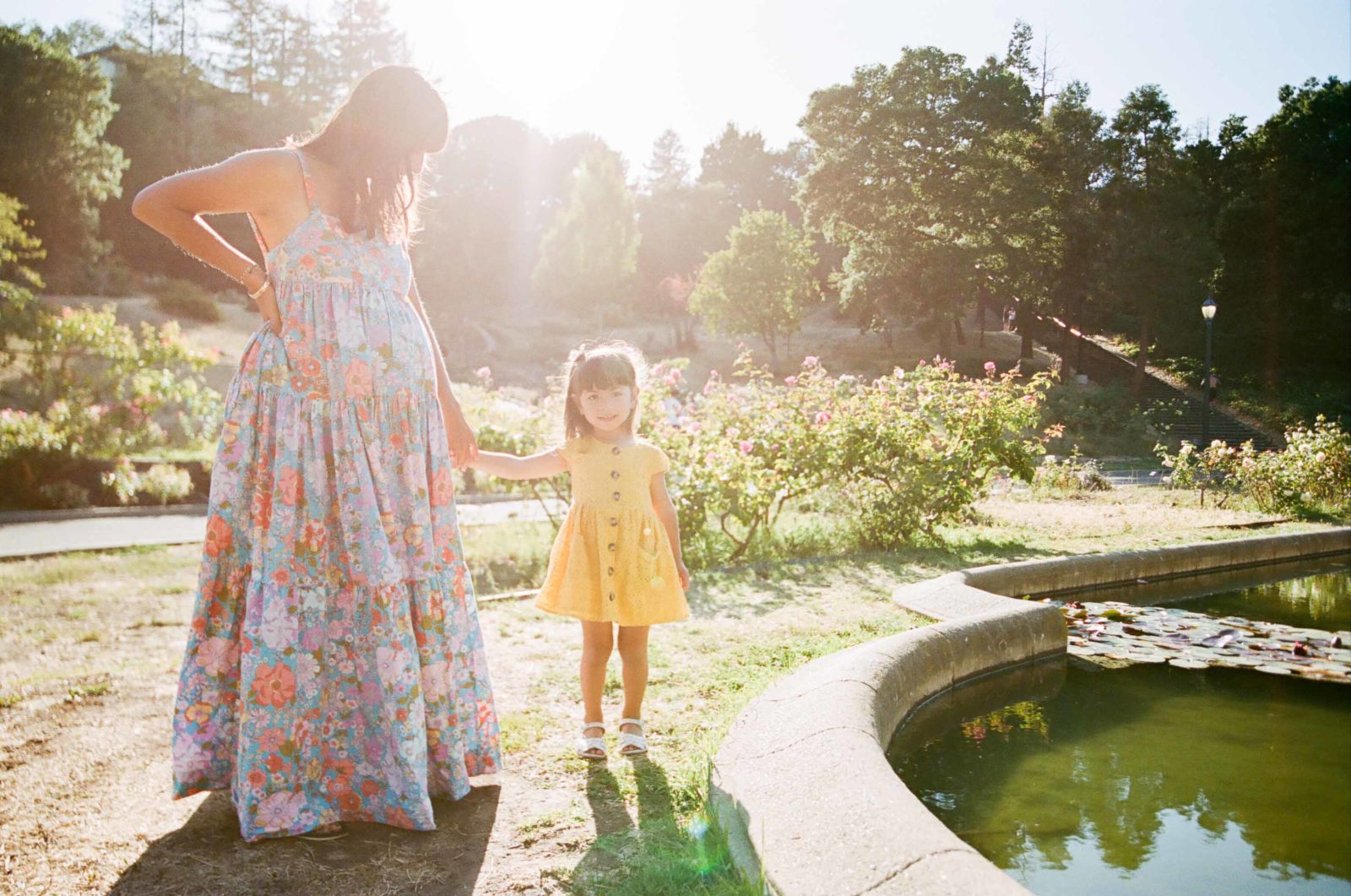 backlit film photo of pregnant mom and toddler girl with sun flare