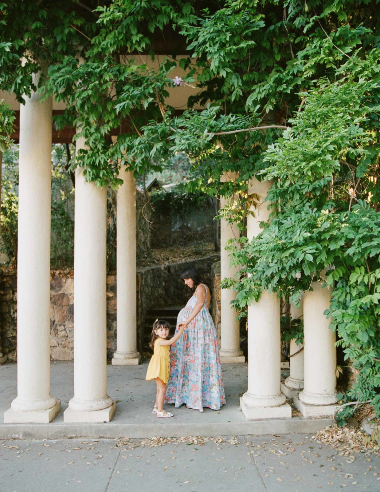 pregnant mother in free people dress standing in between columns