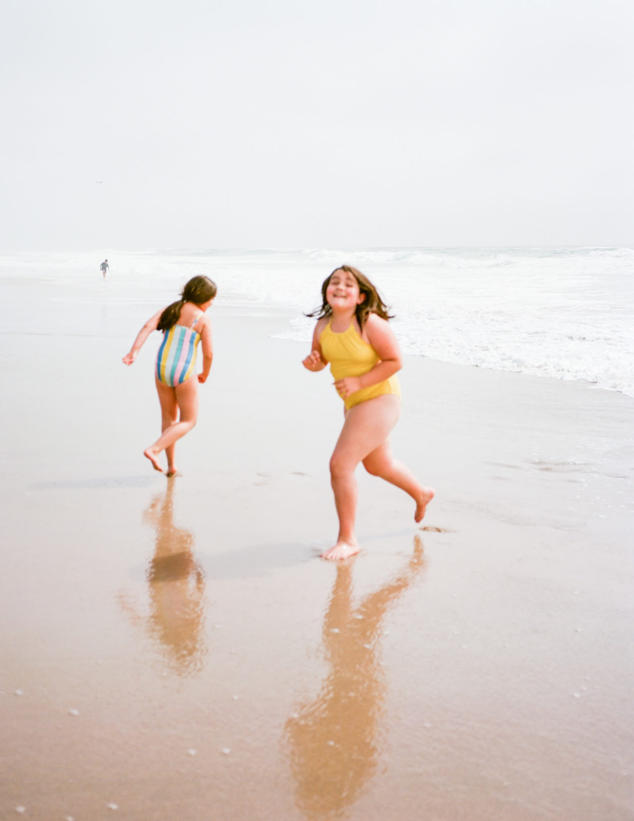 out of focus photo of two girls in bathing suits running on san gregorio state beach