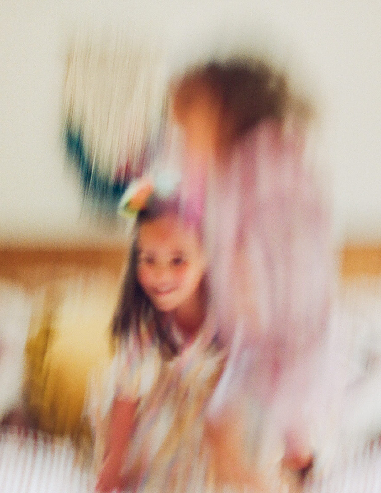 motion blur photo of two girls jumping on a bed