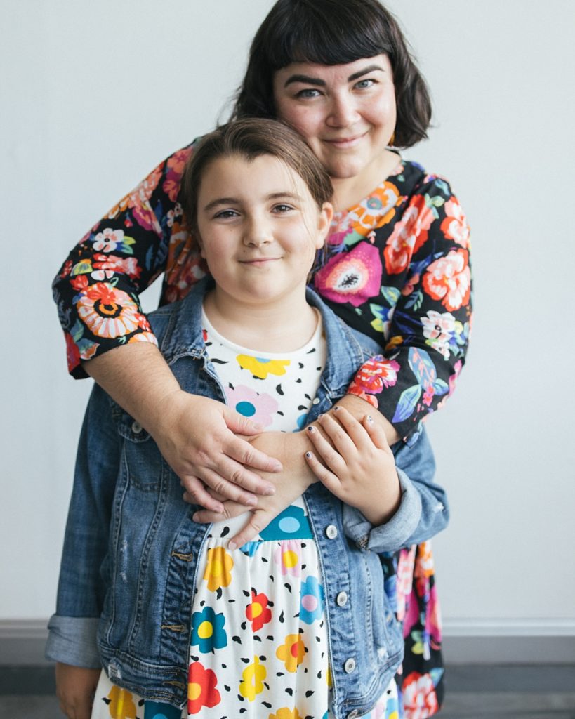 A mom embraces her adorable daughter while posing for family photos and showing tips for mixing patterns in their outfits