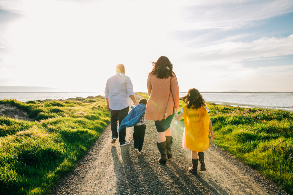 A family walks hand-in-hand along the beautiful waterfront for family photos in the Bay Area with Hi + Hello Photography
