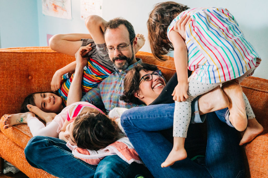 A family plays on the couch together for lifestyle family photos at home