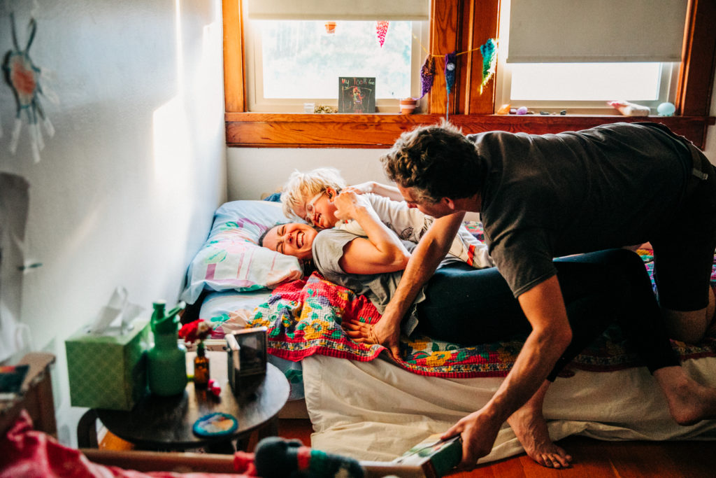 A husband and wife play with their young son in his bedroom during for intimate family photos with San Francisco family photographer Hi + Hello Photography