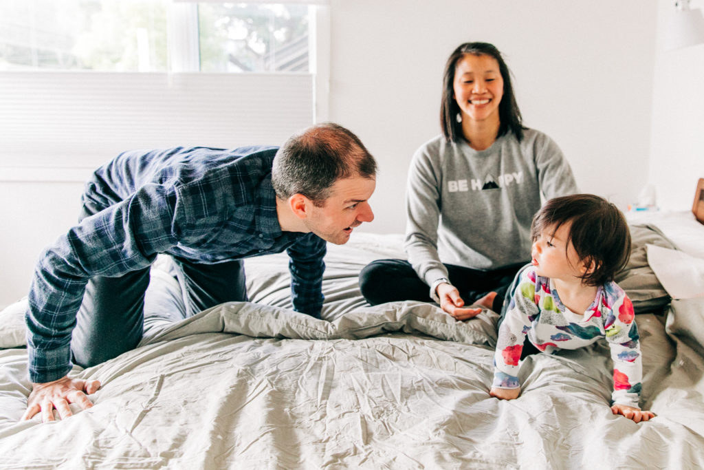 A father and mother play with their toddler in bed during a family photography session with Bay Area family photographer Hi + Hello Photography