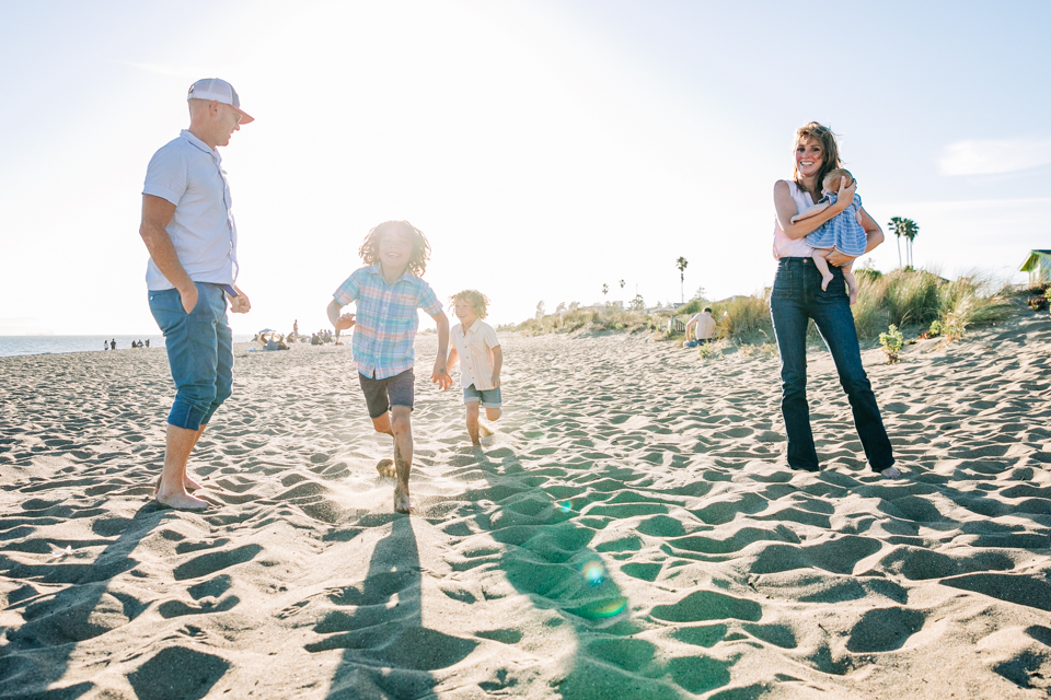 A family of five plays together on a beach in the Bay Area for candid family photographs with Hi + Hello Photography