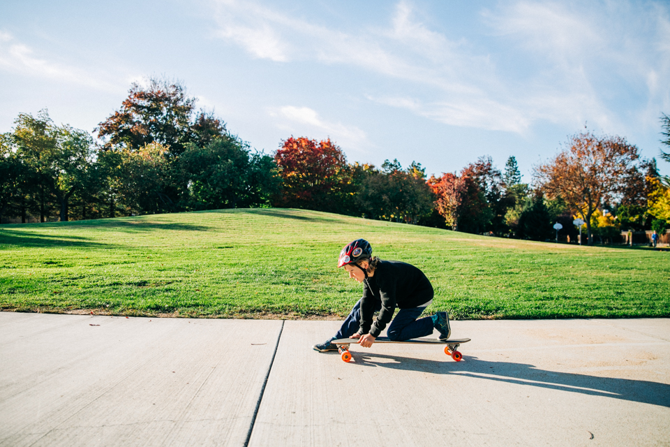 A boy riding a skateboard in a park during an outdoor Bay Area family session