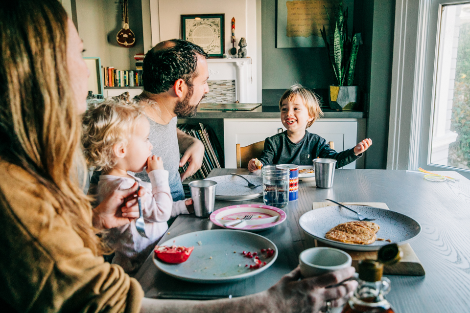 A family of four sits at the dining room table eating breakfast together in the San Francisco Bay Area