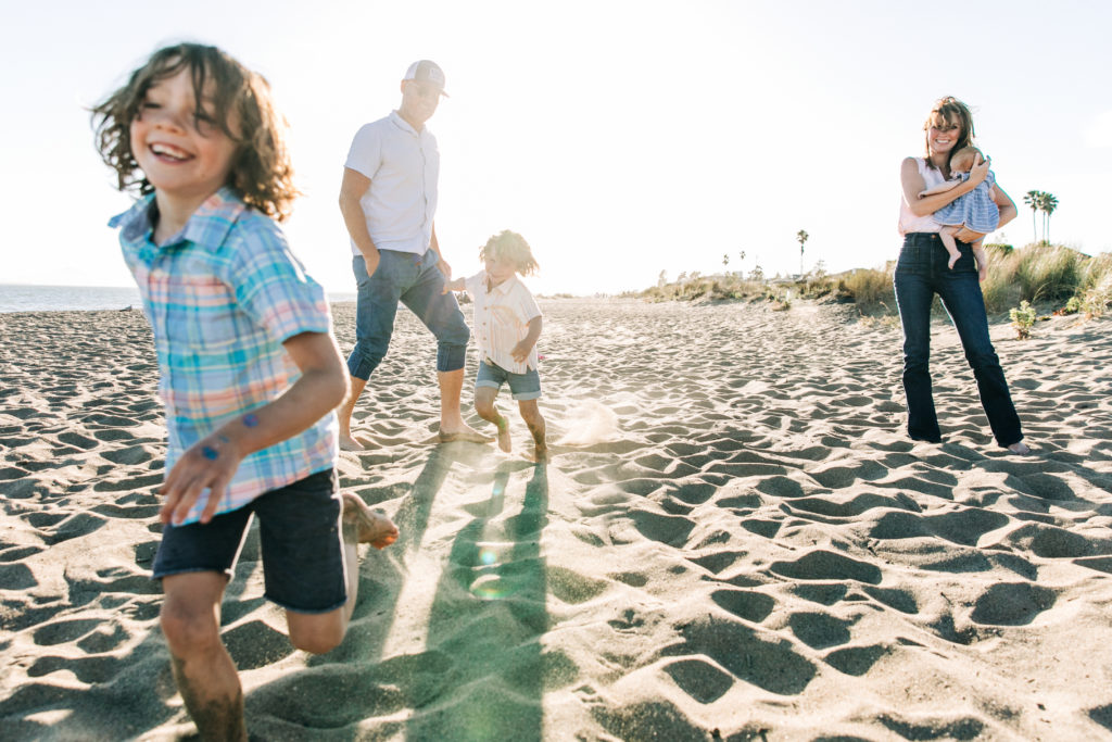 family of 5 on the beach backlit with flare