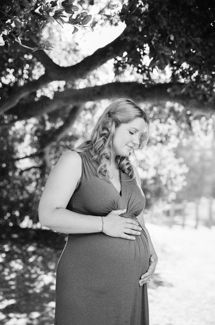 black and white maternity image of woman holding belly and looking down