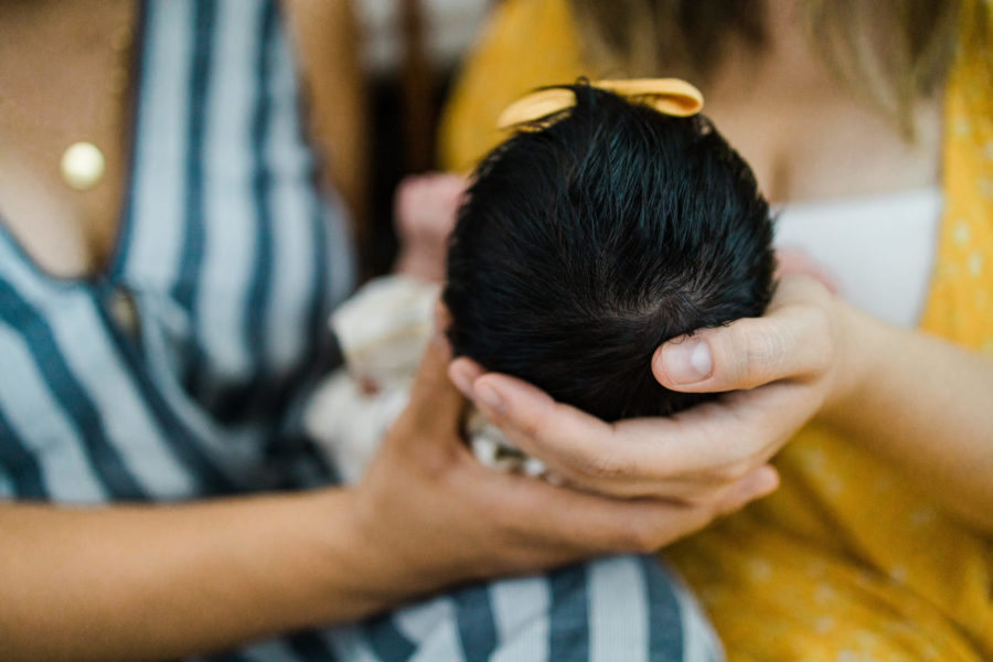 hands holding newborn baby with full head of hair