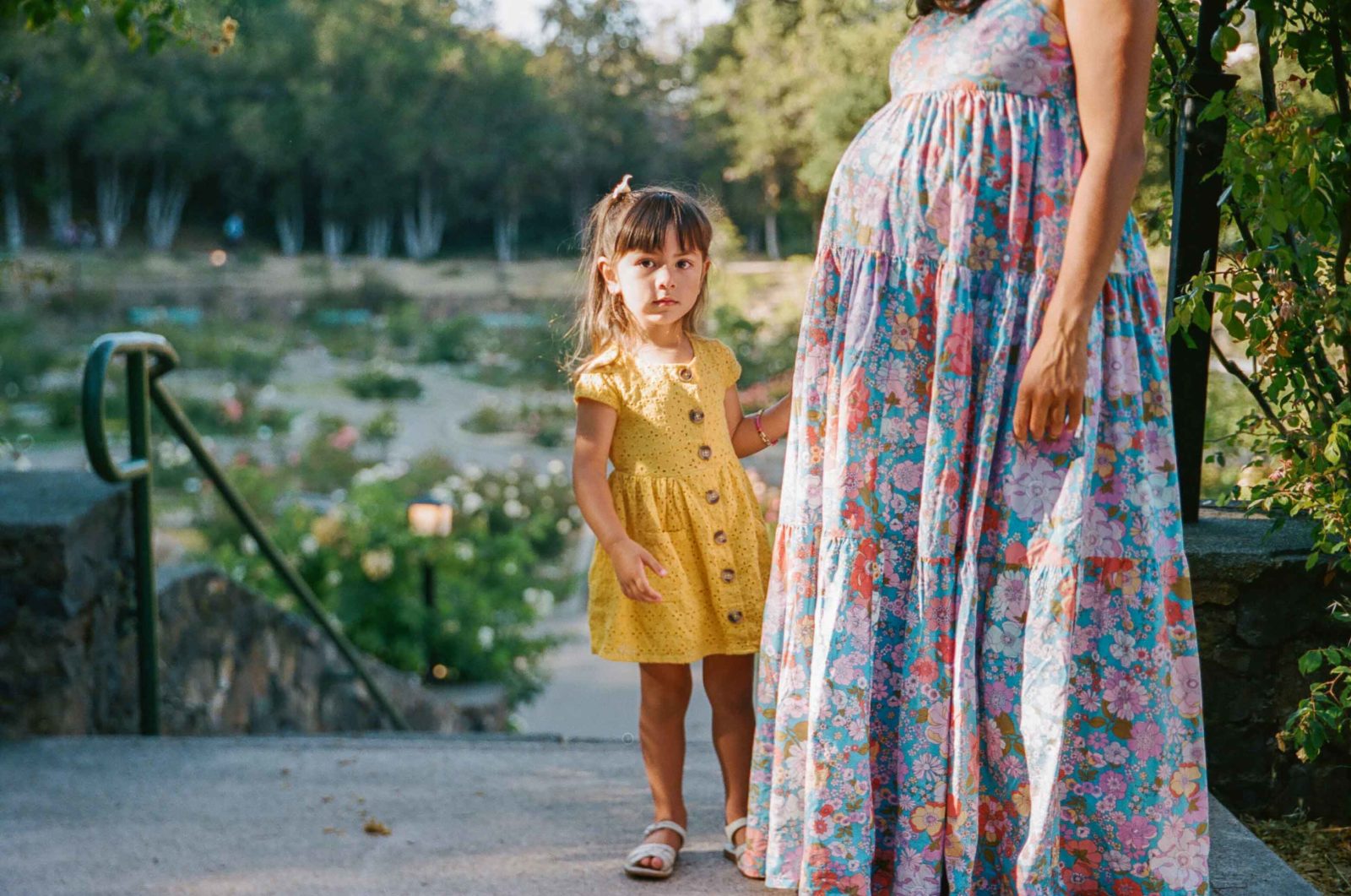 toddler girl standing next to pregnant mom's belly