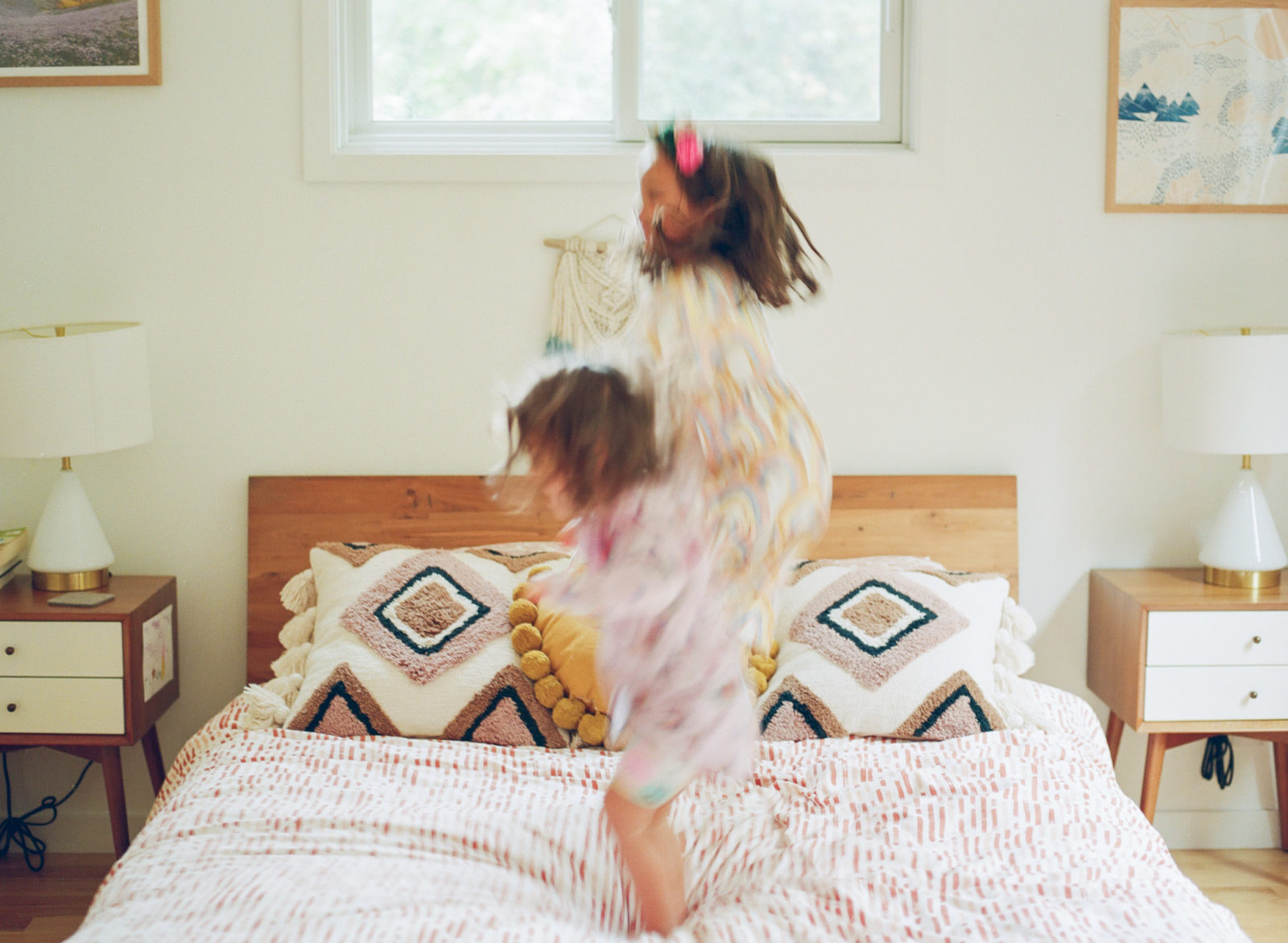 photo of a bedroom with two blurry kids jumping on the bed