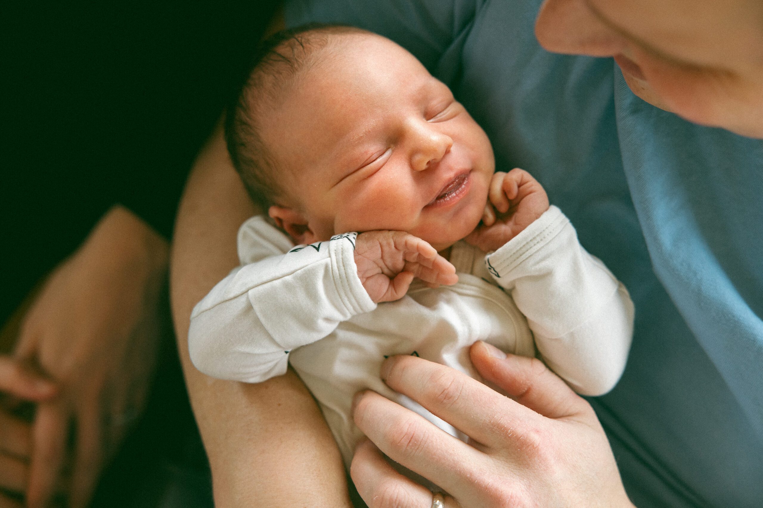 overhead photo of smiling newborn baby girl being held by dad
