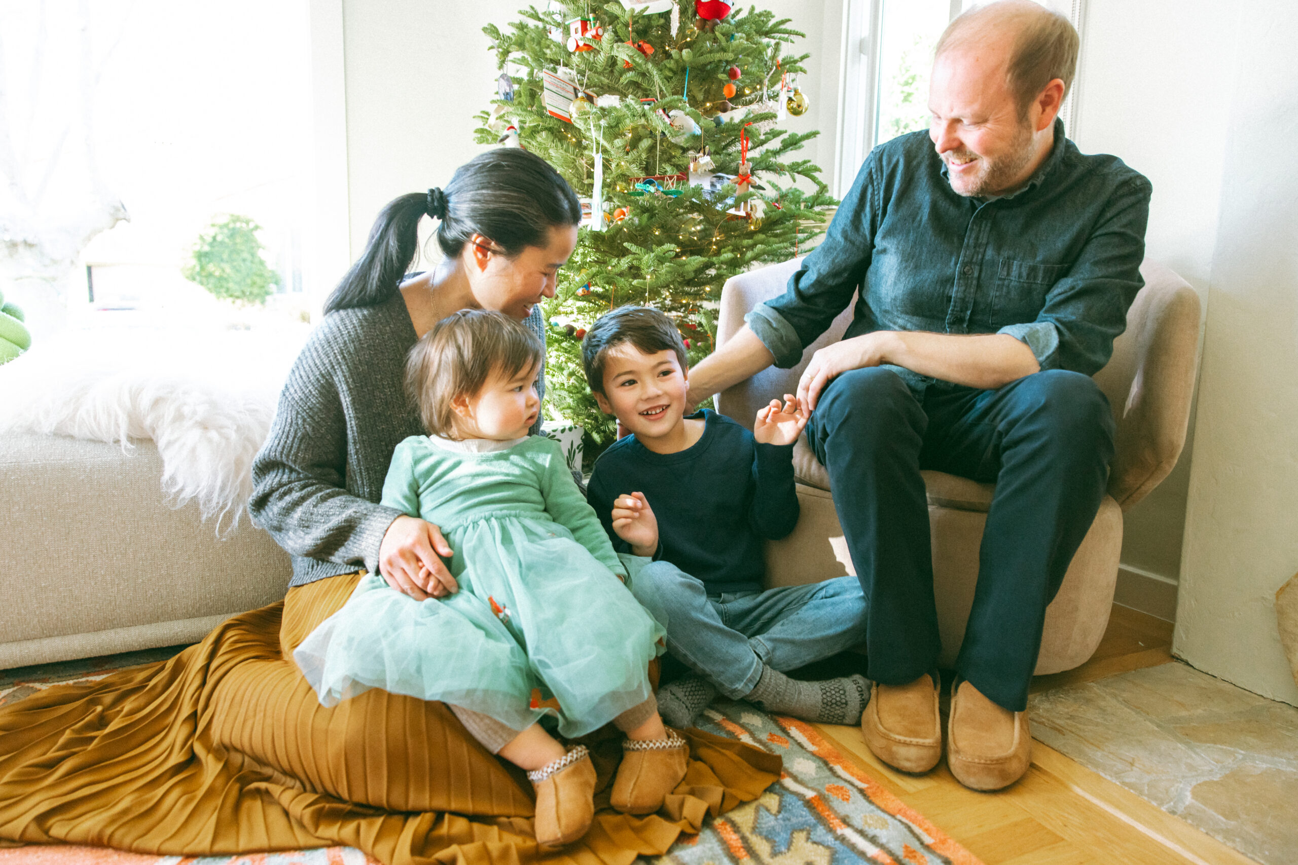 family of four sitting in front of a Christmas Tree in their home